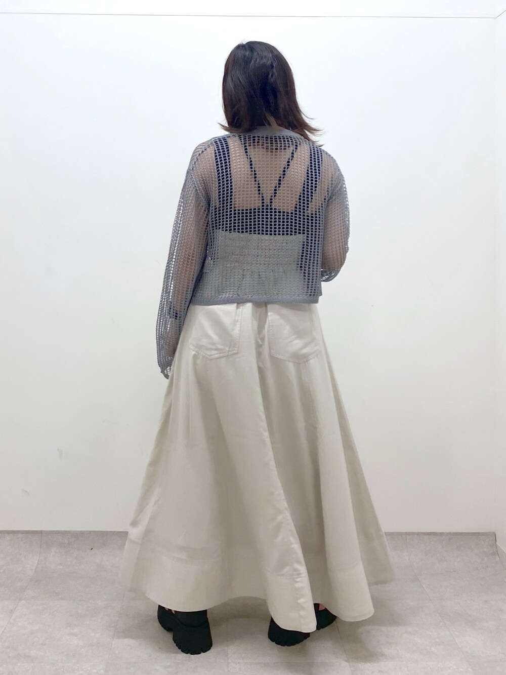 ブラック系のキャミソール、グレー系のカーディガン/ボレロ、ベージュ系のスカートを着用したレディースの春コーディネートの7枚目の写真