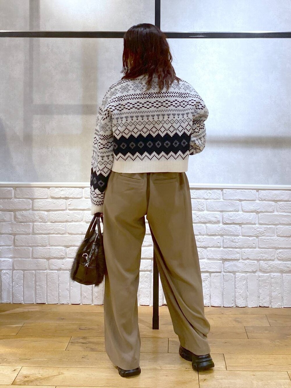 ベージュ系のスラックス、ブラウン系のボストンバッグ、グレー系のニット/セーターを着用したレディースの冬コーディネートの7枚目の写真