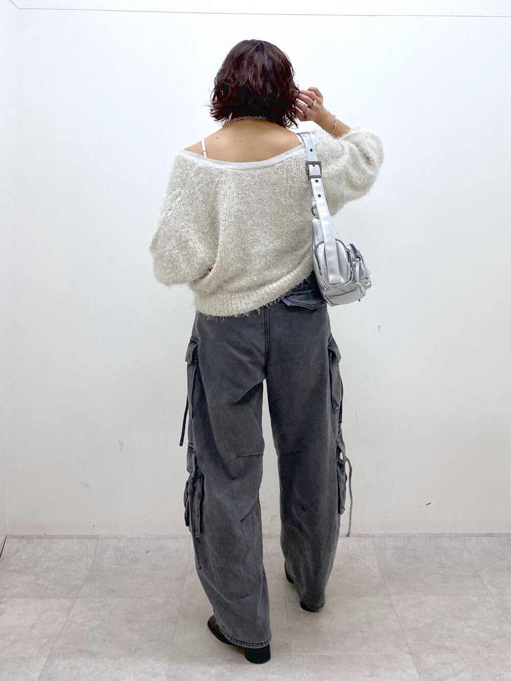 ブラック系のデニムパンツ、ブラック系のブーツ、シルバー系のショルダーバッグを着用したレディースの秋コーディネートの6枚目の写真