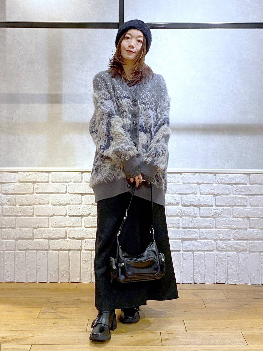 シルバー系のTシャツ/カットソー、ブラック系のブーツ、ブラック系のスカートを着用したレディースの冬コーディネートの9枚目の写真