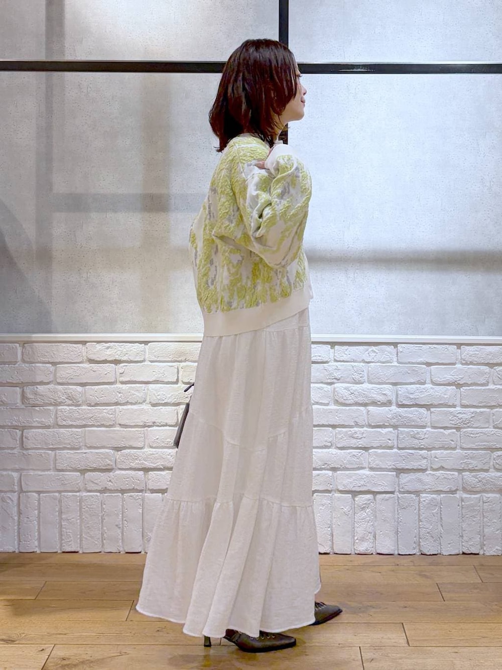 グレー系のショルダーバッグ、ブラウン系のサンダル、ホワイト系のスカートを着用したレディースの冬コーディネートの7枚目の写真