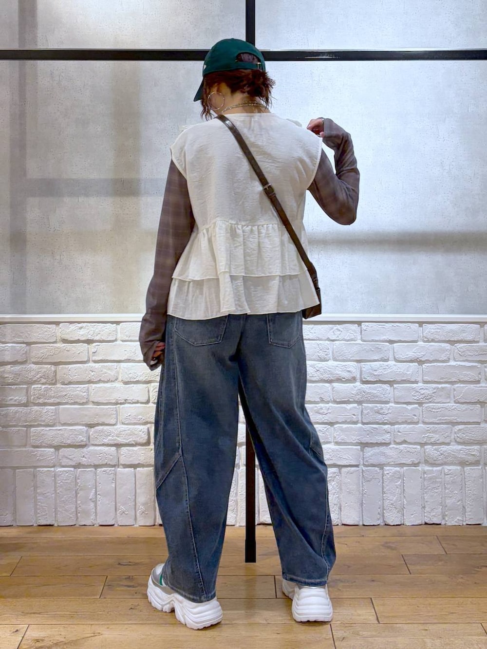 ホワイト系のスニーカー、ブラウン系のショルダーバッグ、ブルー系のデニムパンツを着用したレディースの春コーディネートの6枚目の写真