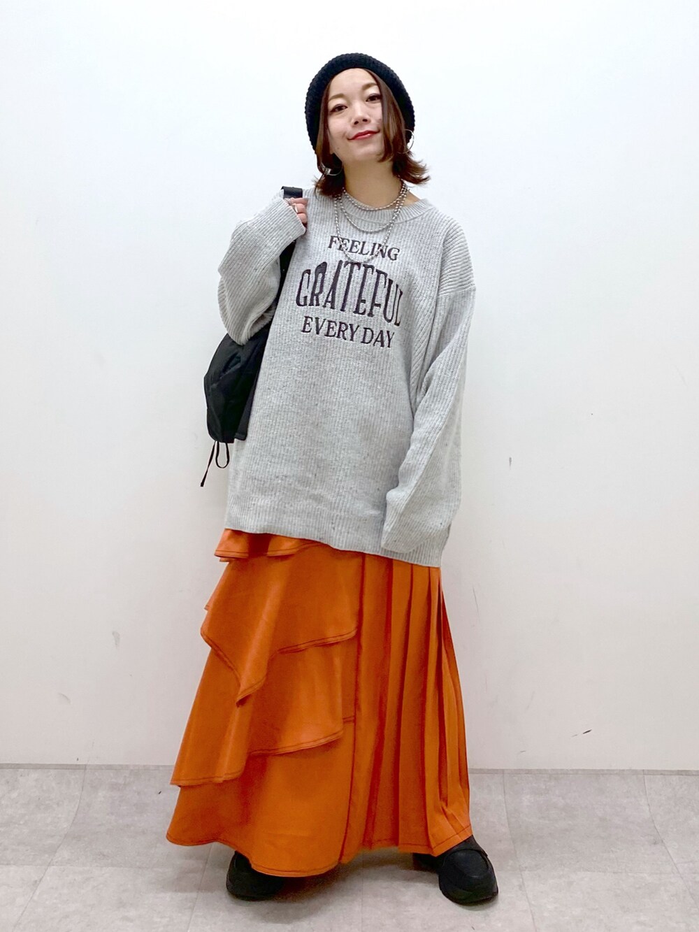 グレー系のニット/セーター、オレンジ系のスカート、ブラック系のローファーを着用したレディースの冬コーディネートの4枚目の写真