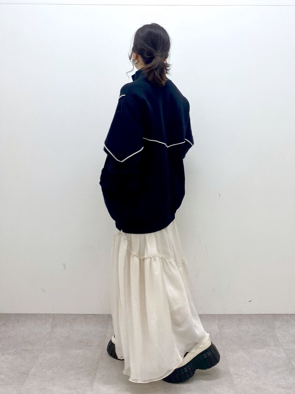 ブラック系のスウェット、ホワイト系のスカート、ホワイト系のローファーを着用したレディースの春コーディネートの6枚目の写真