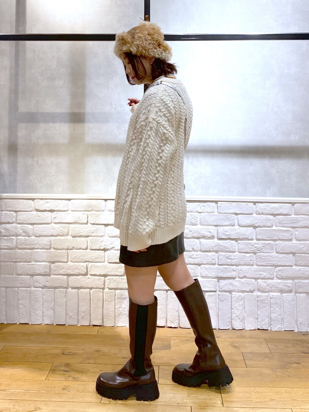 ホワイト系のニット/セーター、ブラック系のスカート、ブラウン系のブーツを着用したレディースの冬コーディネートの7枚目の写真