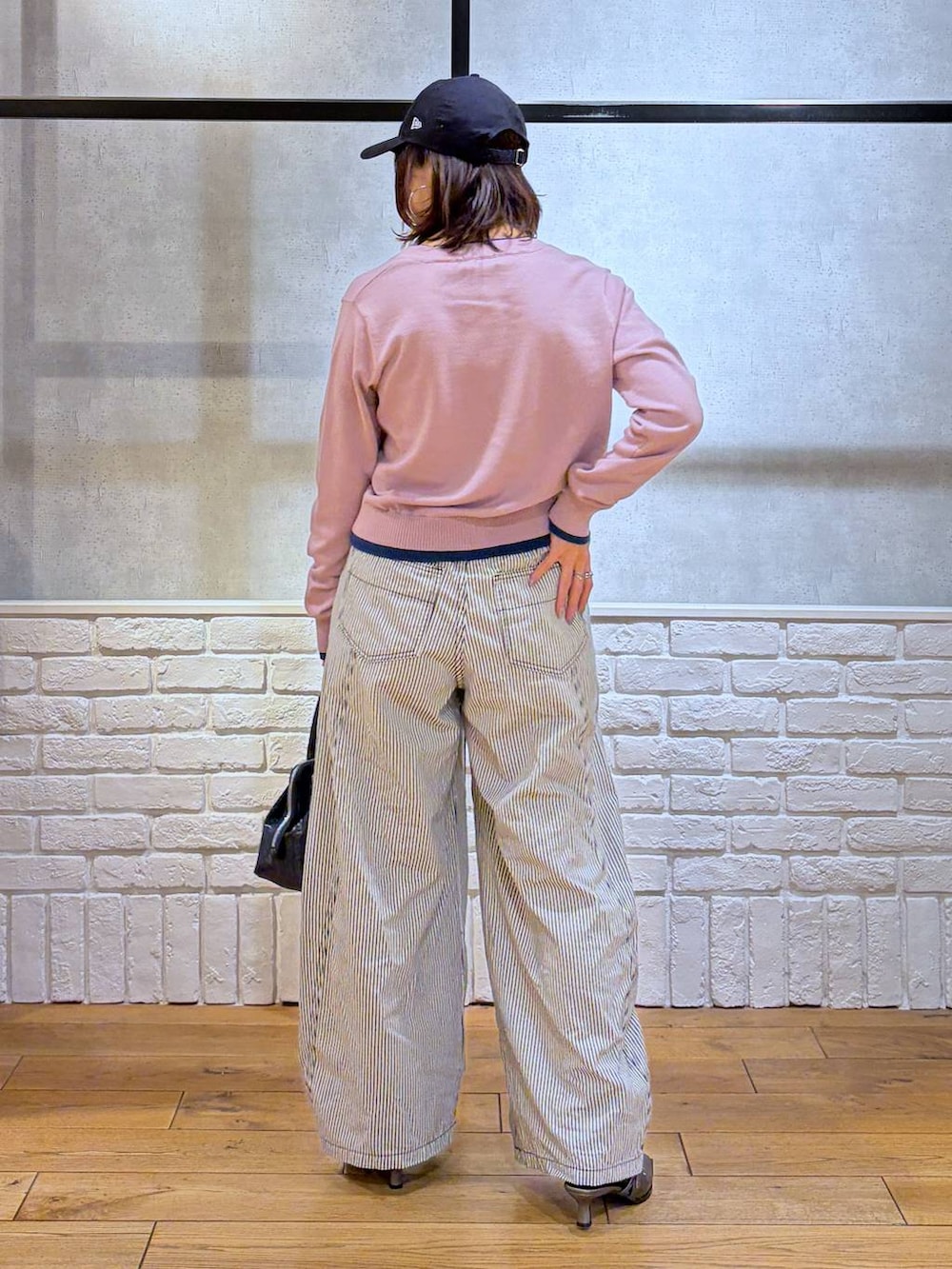 ブルー系のハンドバッグ、ブラウン系のサンダル、ブラック系のデニムパンツを着用したレディースの冬コーディネートの6枚目の写真