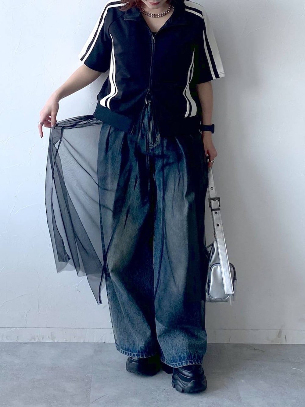 ブラック系のスニーカー、シルバー系のショルダーバッグ、ブルー系のデニムパンツを着用したレディースの夏コーディネートの3枚目の写真