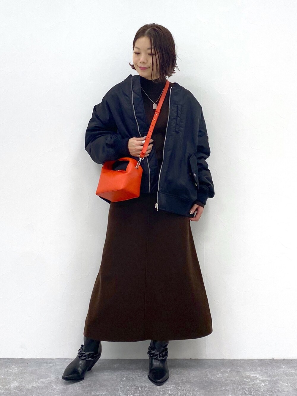 ブラウン系のワンピース、オレンジ系のショルダーバッグ、シルバー系のネックレスを着用したレディースの夏コーディネートの2枚目の写真