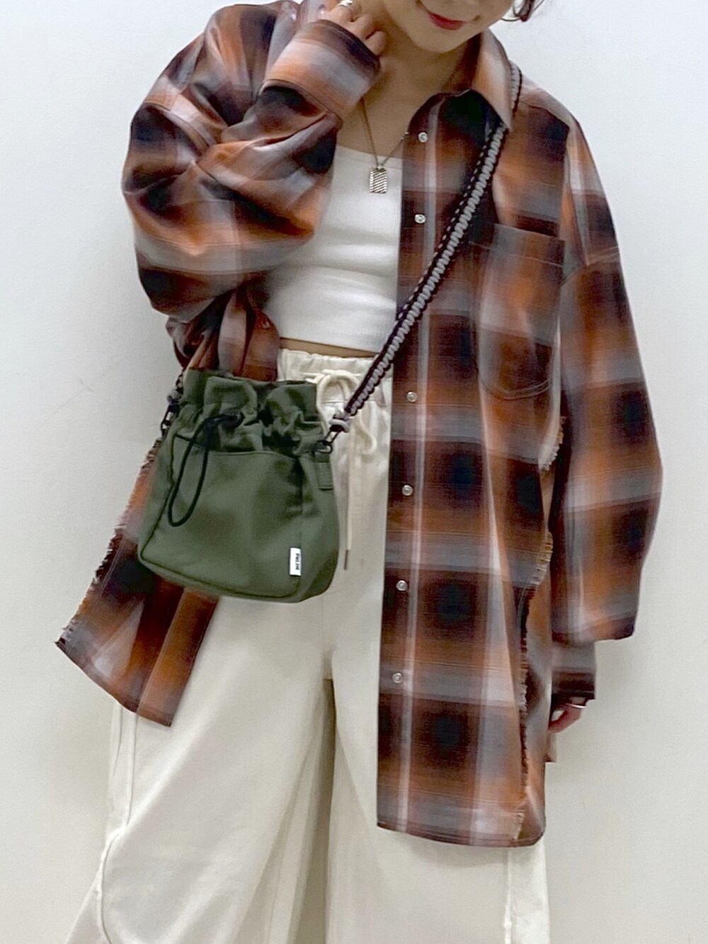 ホワイト系のデニムパンツ、ブラック系のスニーカー、グリーン系のショルダーバッグを着用したレディースの夏コーディネートの2枚目の写真