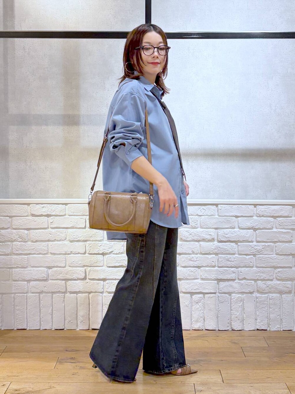 ブルー系のデニムパンツ、ブラウン系のボストンバッグ、イエロー系のサンダルを着用したレディースの春コーディネートの7枚目の写真