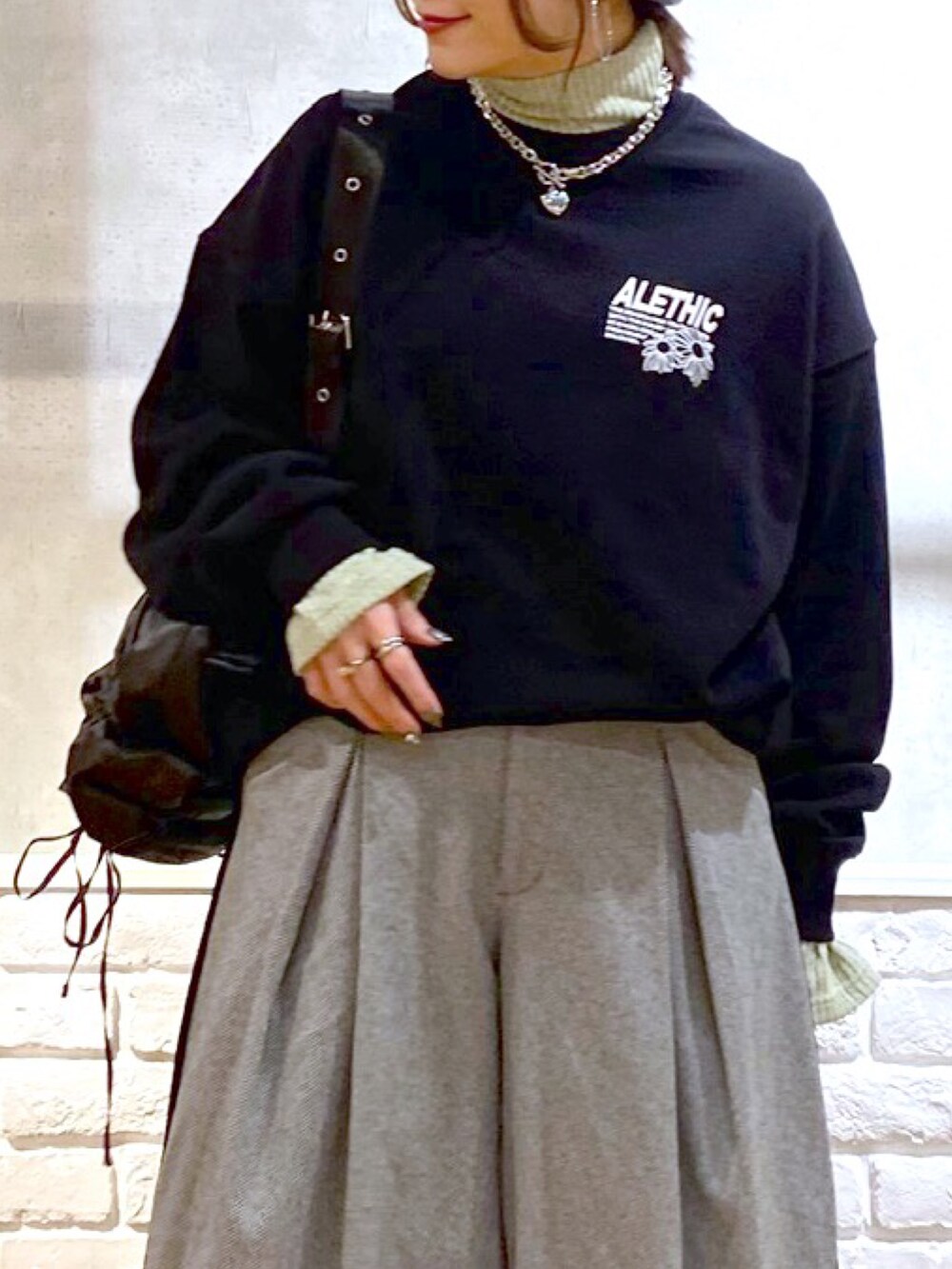 ブラック系のスウェット、グリーン系のショルダーバッグ、ブラック系のスラックスを着用したレディースの秋コーディネートの2枚目の写真