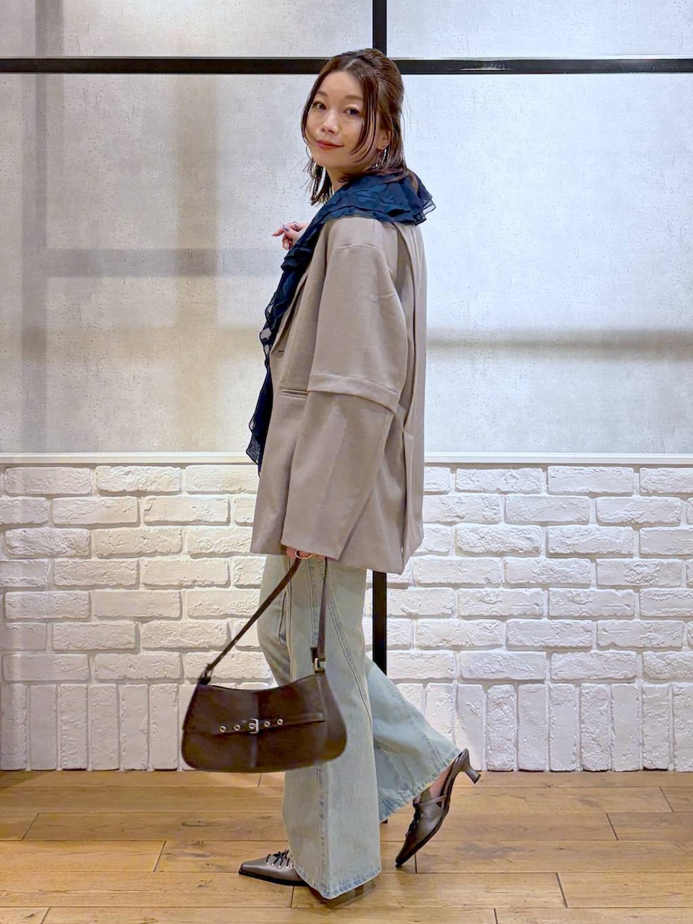 ブラック系のキャミソール、ブルー系のデニムパンツ、ブラウン系のハンドバッグを着用したレディースの春コーディネートの5枚目の写真