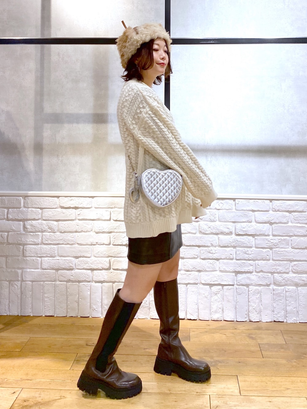 ホワイト系のニット/セーター、ブラック系のスカート、ブラウン系のブーツを着用したレディースの冬コーディネートの5枚目の写真