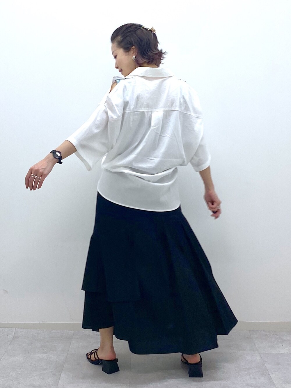 ブラック系のスカート、ブラック系のサンダル、ホワイト系のシャツ/ブラウスを着用したレディースの夏コーディネートの3枚目の写真