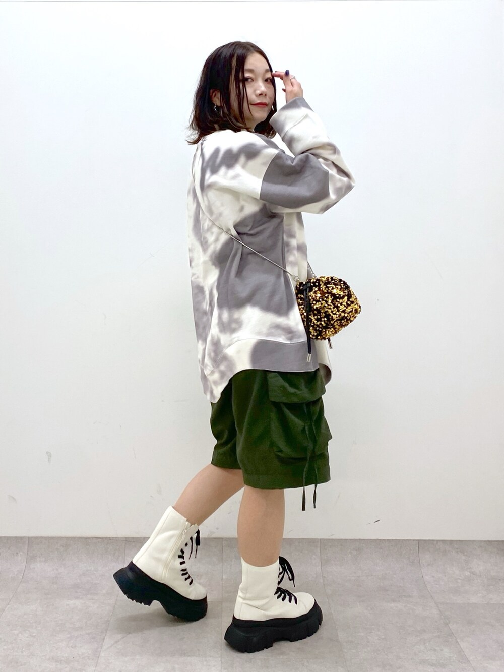 グリーン系のカーゴパンツ、ホワイト系のブーツ、ゴールド系のショルダーバッグを着用したレディースの冬コーディネートの8枚目の写真