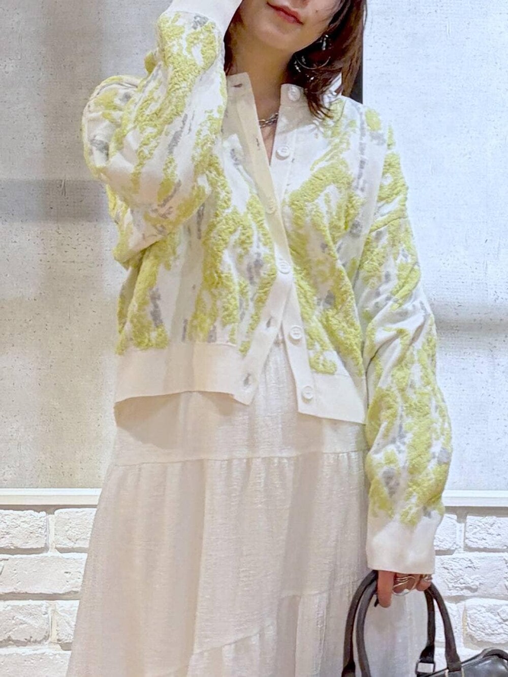 グレー系のショルダーバッグ、ブラウン系のサンダル、ホワイト系のスカートを着用したレディースの冬コーディネートの2枚目の写真