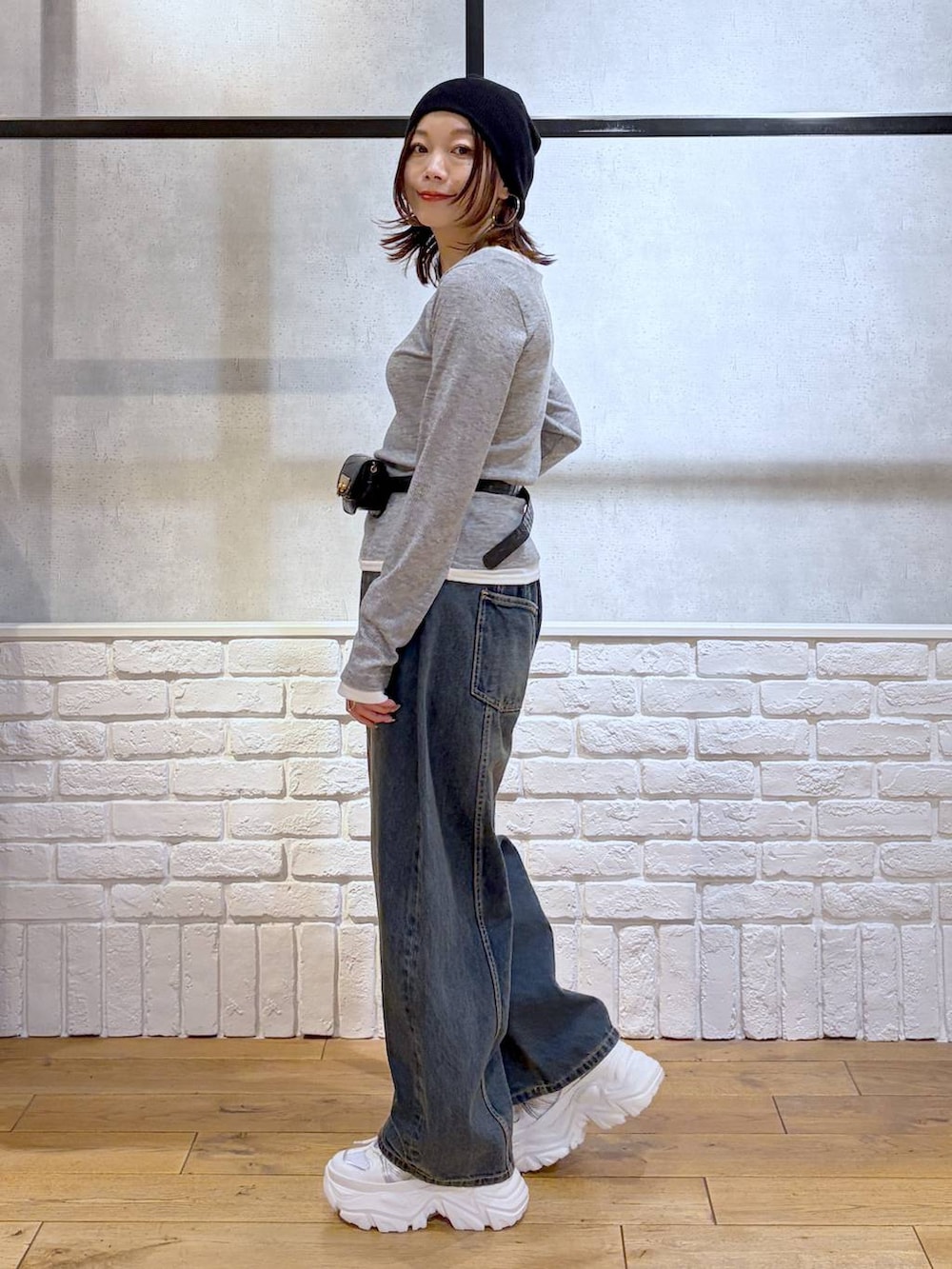 ホワイト系のスニーカー、ブラック系のボディバッグ/ウエストポーチ、ブルー系のデニムパンツを着用したレディースの春コーディネートの5枚目の写真