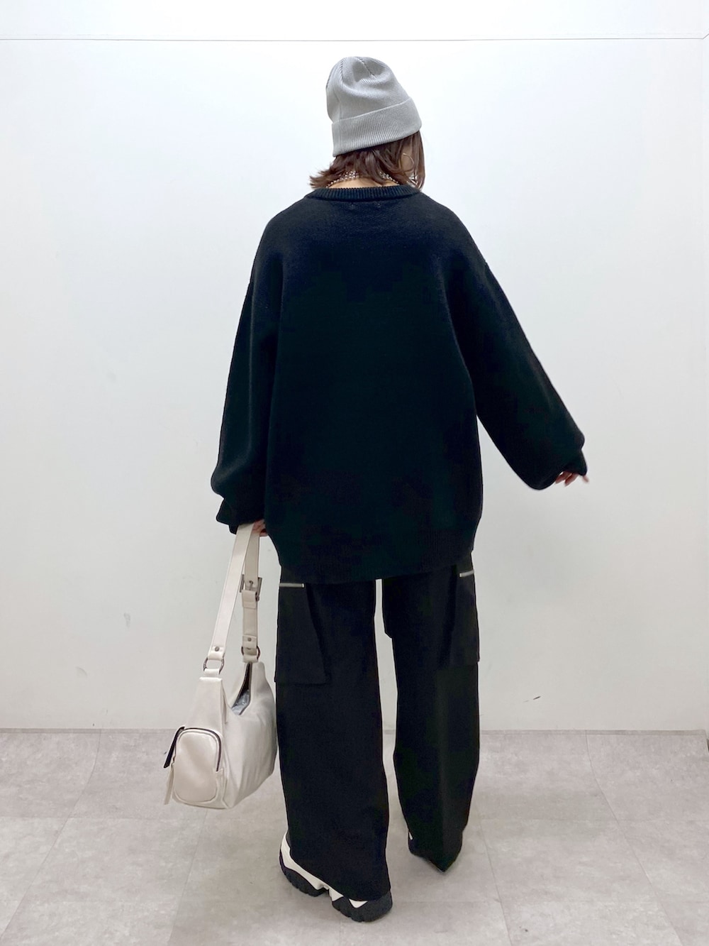 ブラック系のニット/セーター、ブラック系のカーゴパンツ、ホワイト系のショルダーバッグを着用したレディースの冬コーディネートの6枚目の写真
