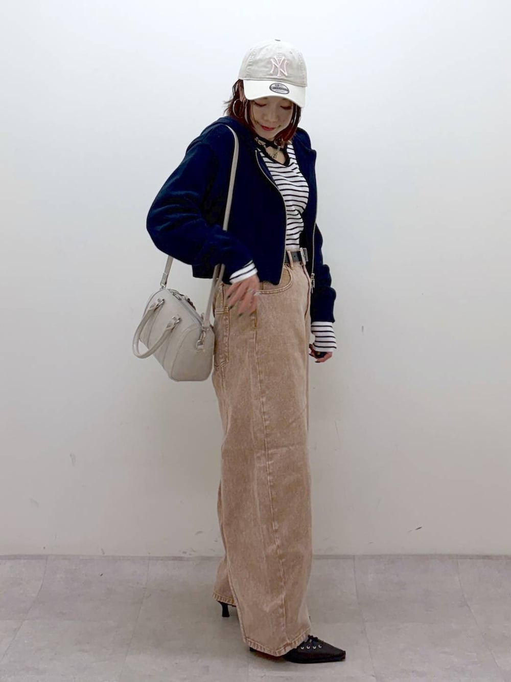 ブラウン系のデニムパンツ、ブラウン系のデニムパンツ、ホワイト系のボストンバッグを着用したレディースの冬コーディネートの3枚目の写真