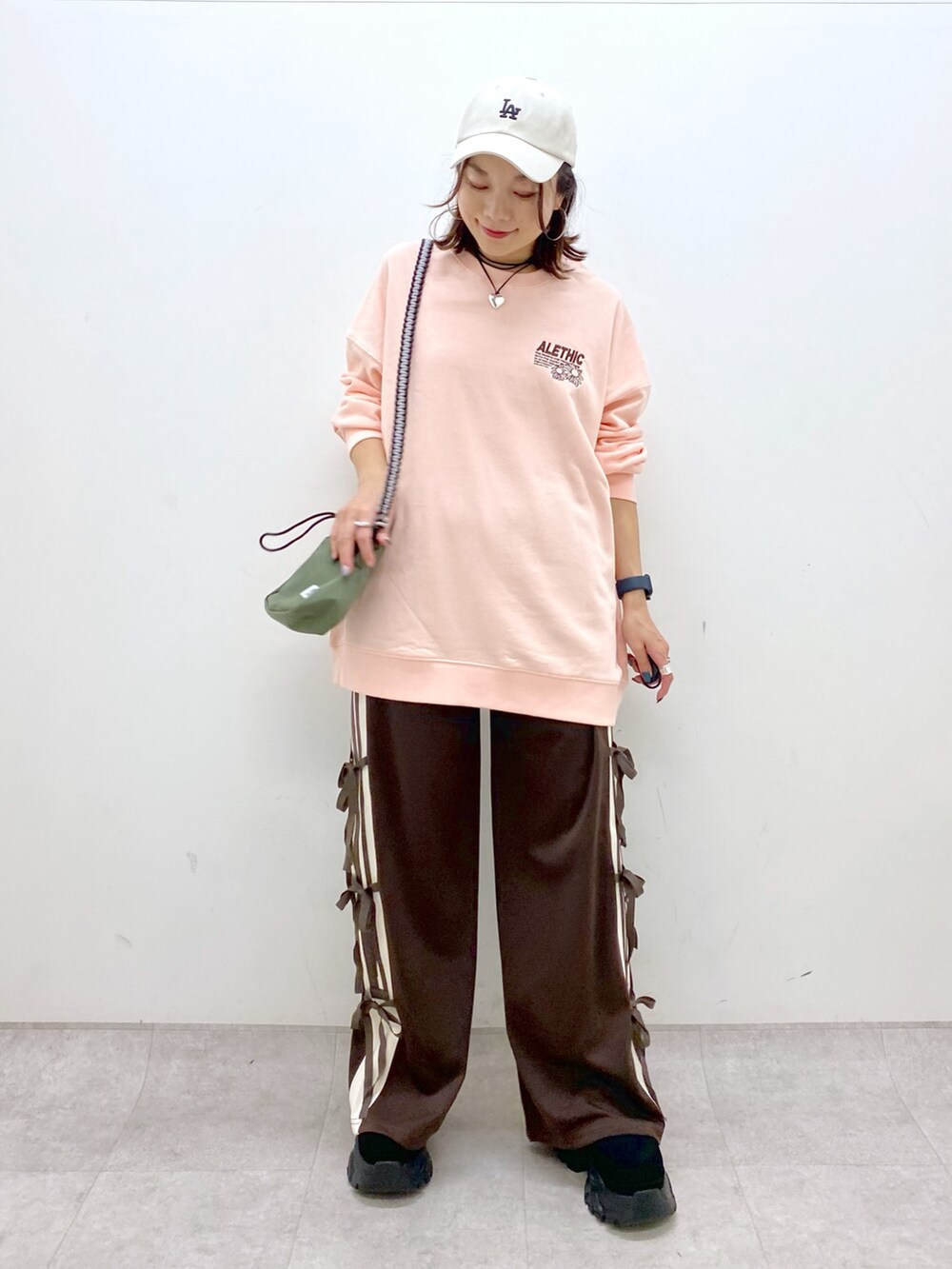 ピンク系のスウェット、グリーン系のショルダーバッグ、ブラウン系のその他パンツを着用したレディースの夏コーディネートの5枚目の写真