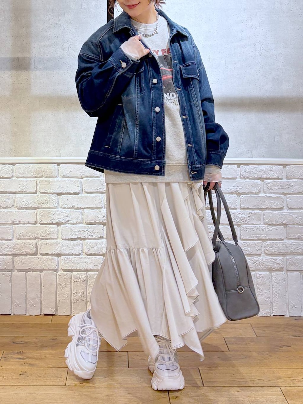 ホワイト系のスニーカー、グレー系のボストンバッグ、ベージュ系のスカートを着用したレディースの冬コーディネートの2枚目の写真