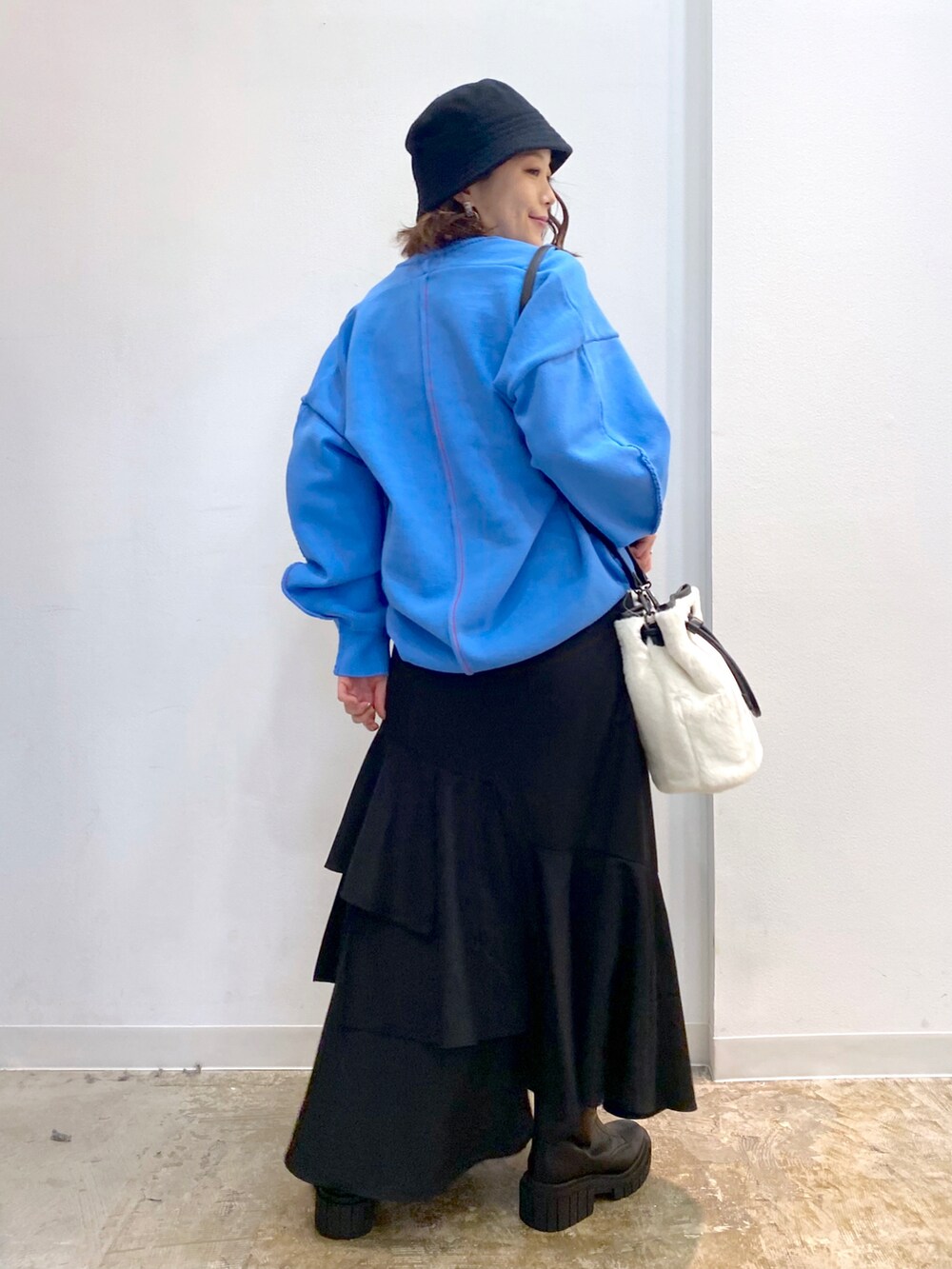 ホワイト系のショルダーバッグ、ブルー系のニット/セーター、ブラック系のスカートを着用したレディースの秋コーディネートの5枚目の写真