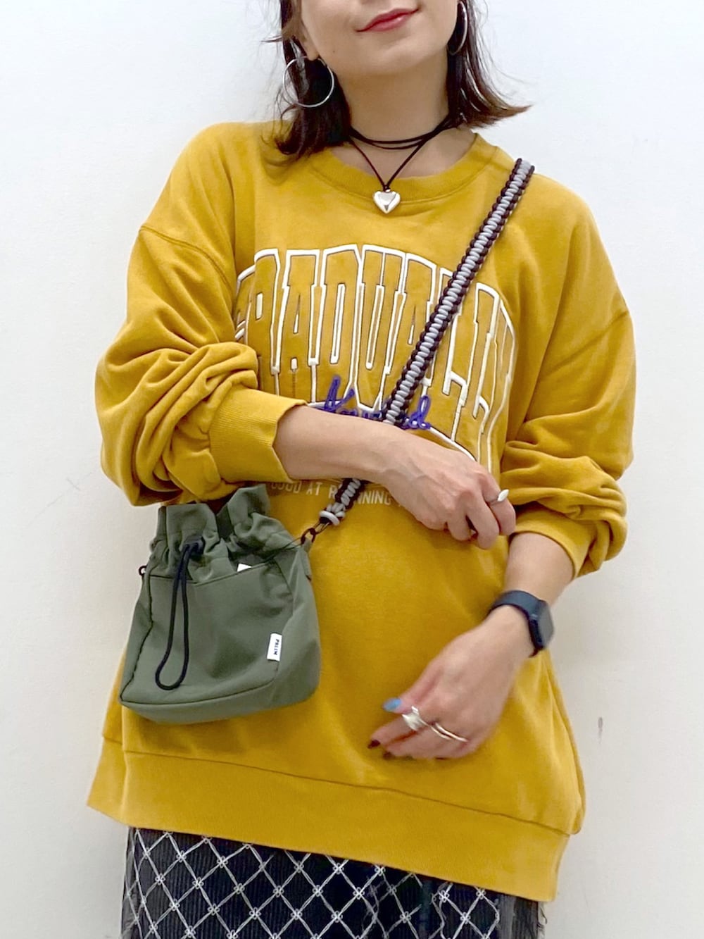 イエロー系のスウェット、ブラック系のデニムパンツ、ホワイト系のスニーカーを着用したレディースの夏コーディネートの2枚目の写真