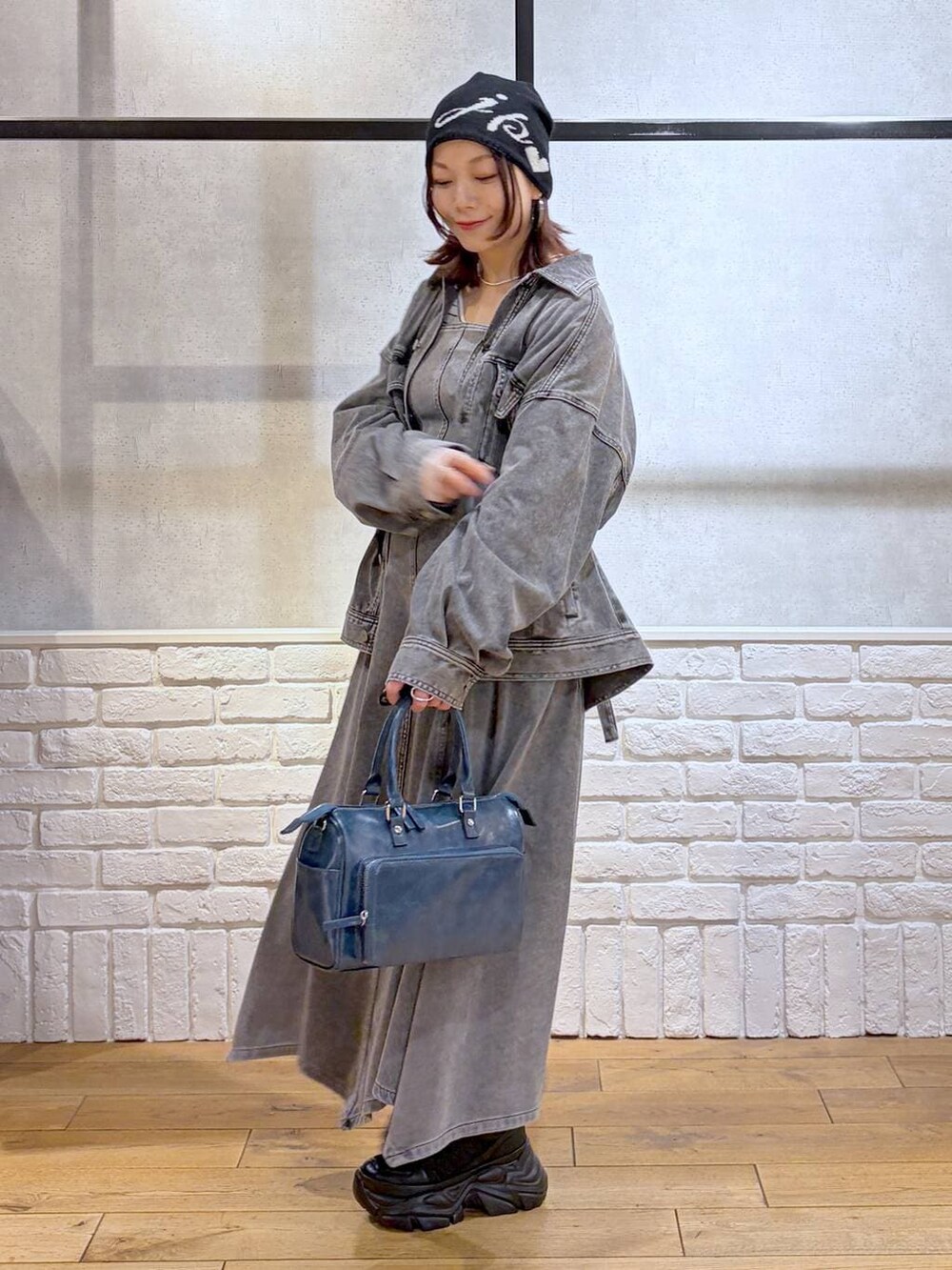 ブラック系のスニーカー、ブルー系のハンドバッグ、ブラック系のブルゾンを着用したレディースの冬コーディネートの7枚目の写真