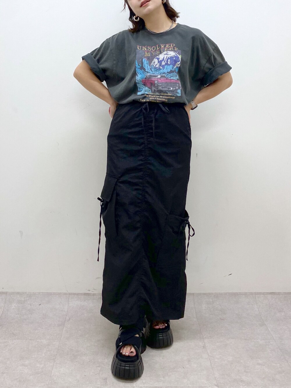 グレー系のTシャツ/カットソー、ブラック系のスカート、ブラック系のスニーカーを着用したレディースの夏コーディネートの3枚目の写真