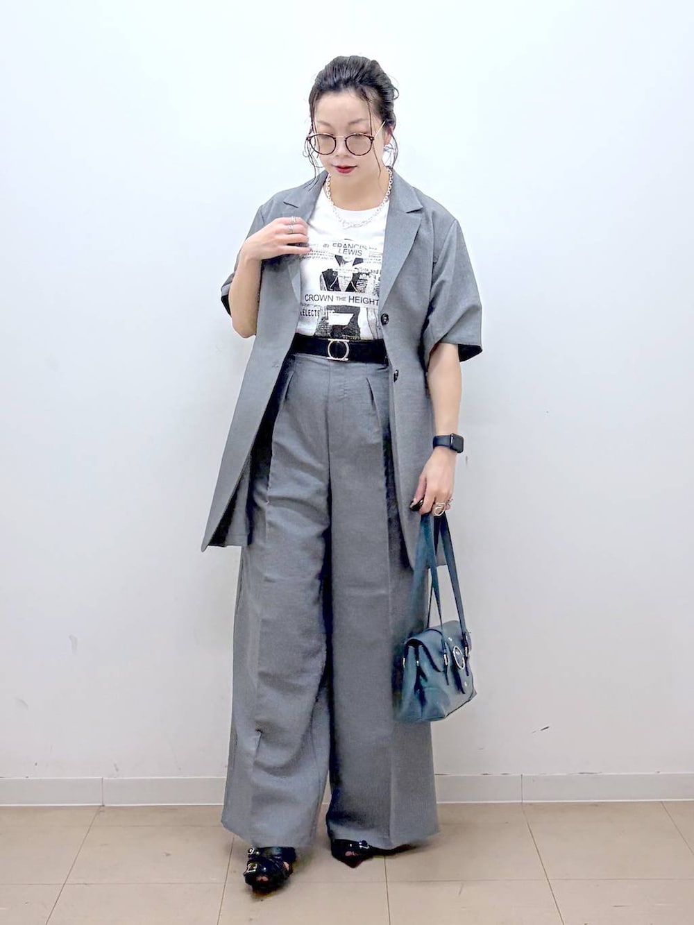 ホワイト系のTシャツ/カットソー、グレー系のスラックス、ブラック系のサンダルを着用したレディースの夏コーディネートの8枚目の写真