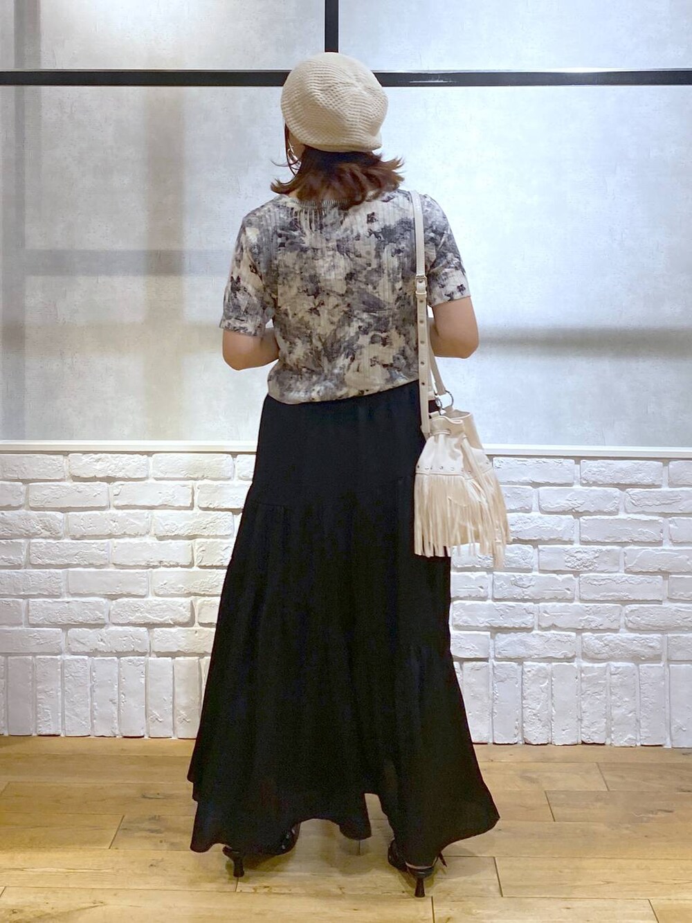 ブラック系のパンプス、ブラック系のスカート、ホワイト系のショルダーバッグを着用したレディースの夏コーディネートの6枚目の写真