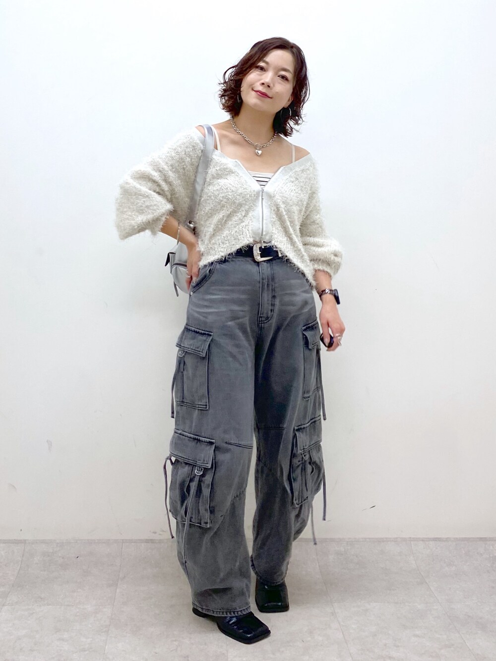 ブラック系のデニムパンツ、ブラック系のブーツ、シルバー系のショルダーバッグを着用したレディースの秋コーディネートの9枚目の写真