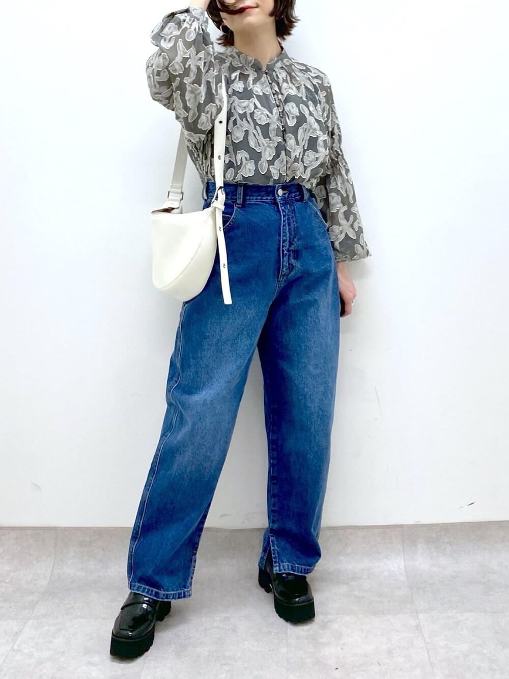 ブルー系のパンツ、グレー系のトップス、ホワイト系のショルダーバッグを着用したレディースの春コーディネートの4枚目の写真