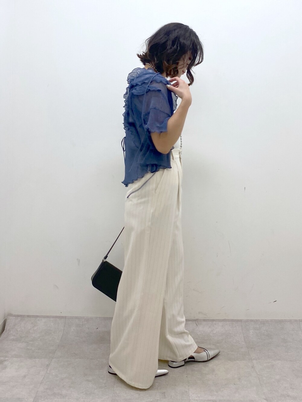 ホワイト系のスラックス、ブラック系のハンドバッグ、シルバー系のパンプスを着用したレディースの夏コーディネートの7枚目の写真