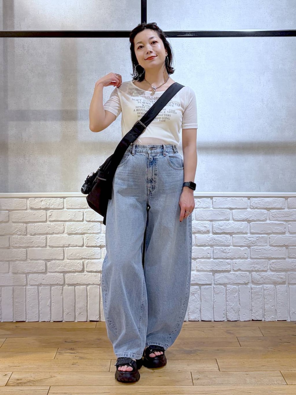 ブラック系のボストンバッグ、ブルー系のデニムパンツ、ブラック系のサンダルを着用したレディースの春コーディネートの4枚目の写真