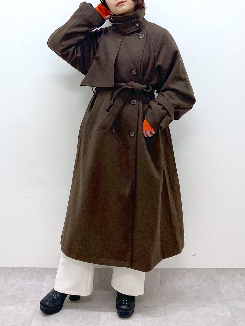 ブラック系のトップス、オレンジ系のトップス、ホワイト系のパンツを着用したレディースの秋コーディネートの4枚目の写真