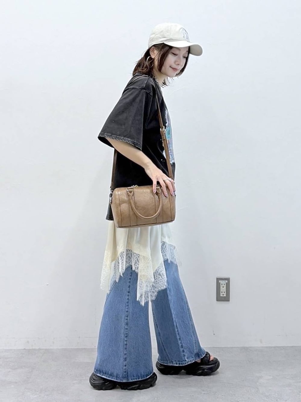 ブルー系のデニムパンツ、ブラウン系のボストンバッグ、ホワイト系のチュニックを着用したレディースの春コーディネートの5枚目の写真