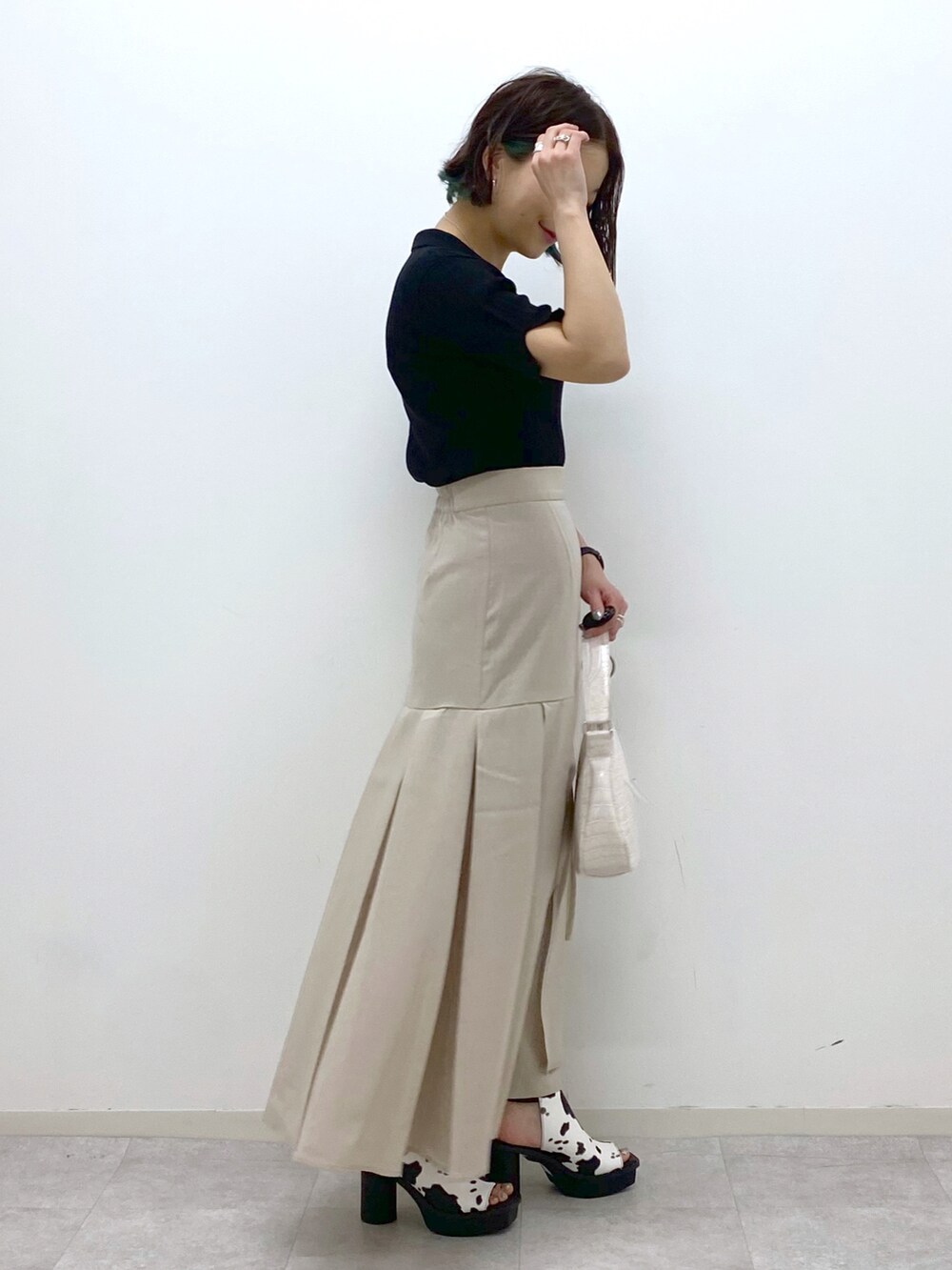 ホワイト系のショルダーバッグ、ベージュ系のスカート、ホワイト系のサンダルを着用したレディースの春コーディネートの3枚目の写真