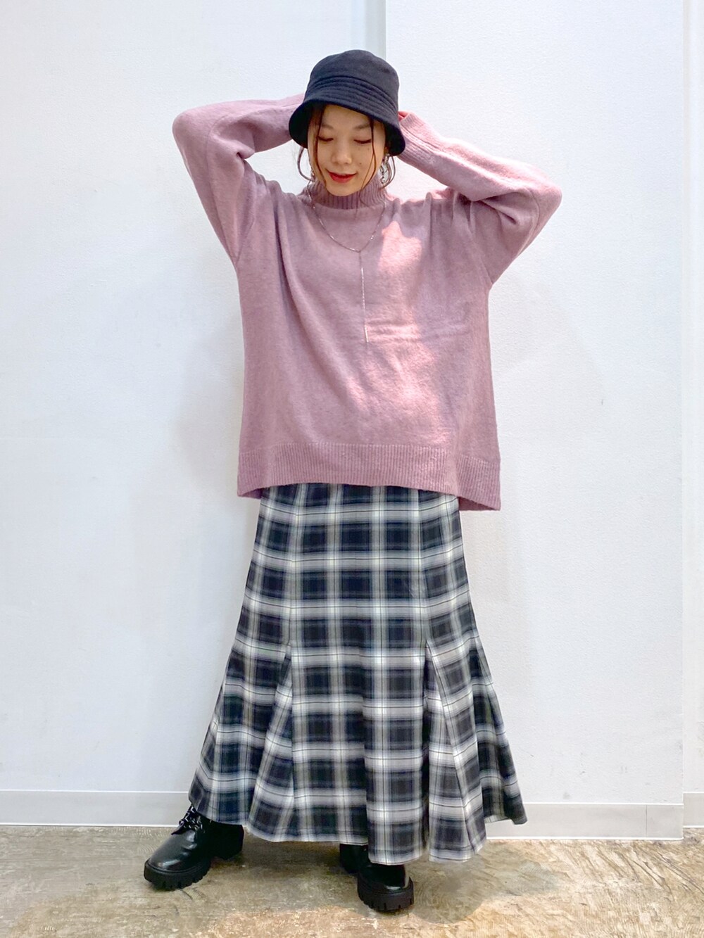 ピンク系のニット/セーター、ブラック系のスカート、ブラック系のブーツを着用したレディースの冬コーディネートの2枚目の写真