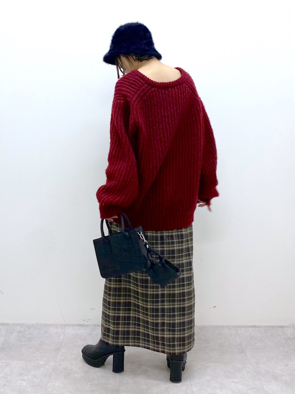 レッド系のニット/セーター、グリーン系のスカート、ブラック系のブーツを着用したレディースの冬コーディネートの3枚目の写真