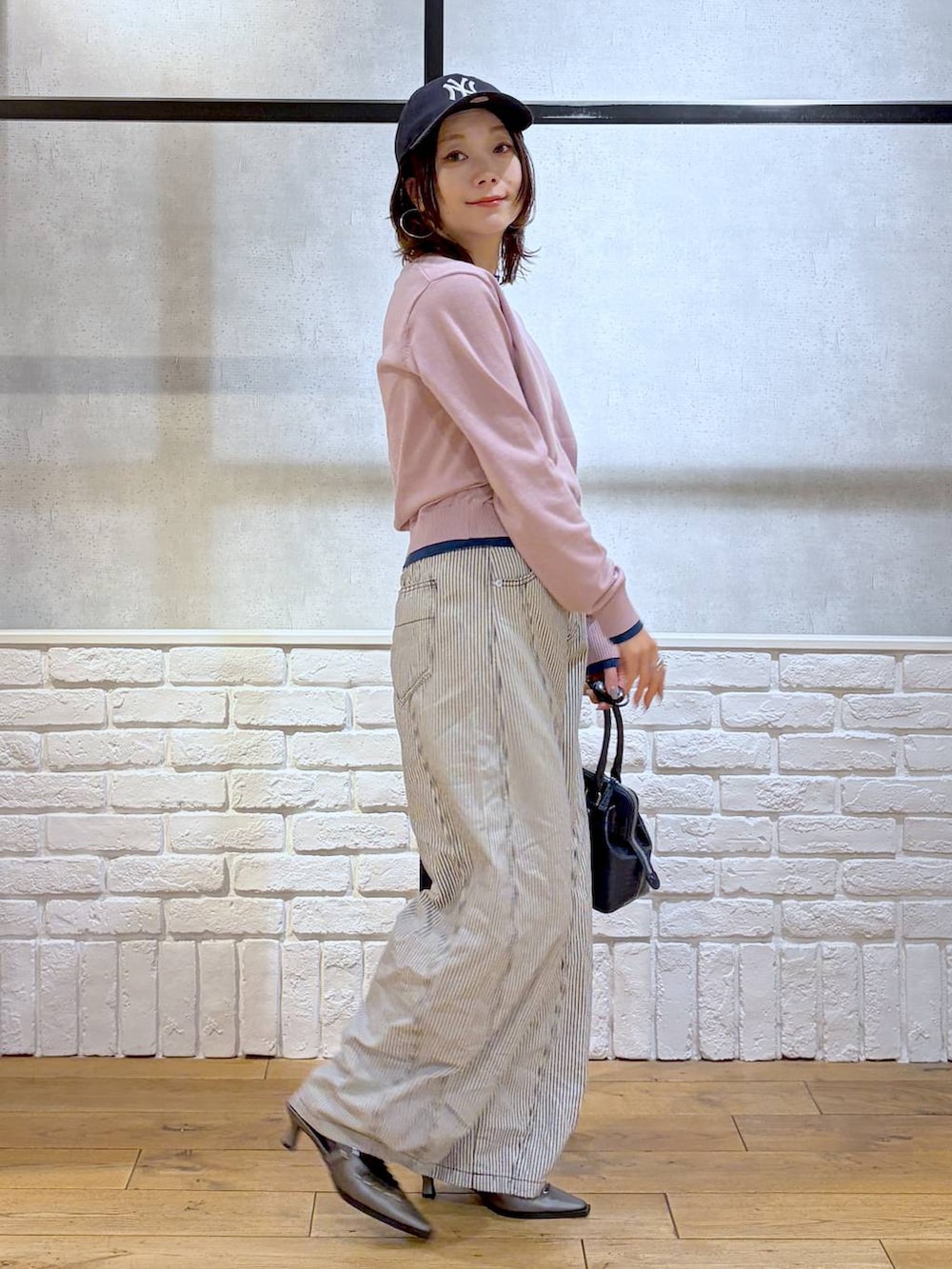 ブルー系のハンドバッグ、ブラウン系のサンダル、ブラック系のデニムパンツを着用したレディースの冬コーディネートの5枚目の写真