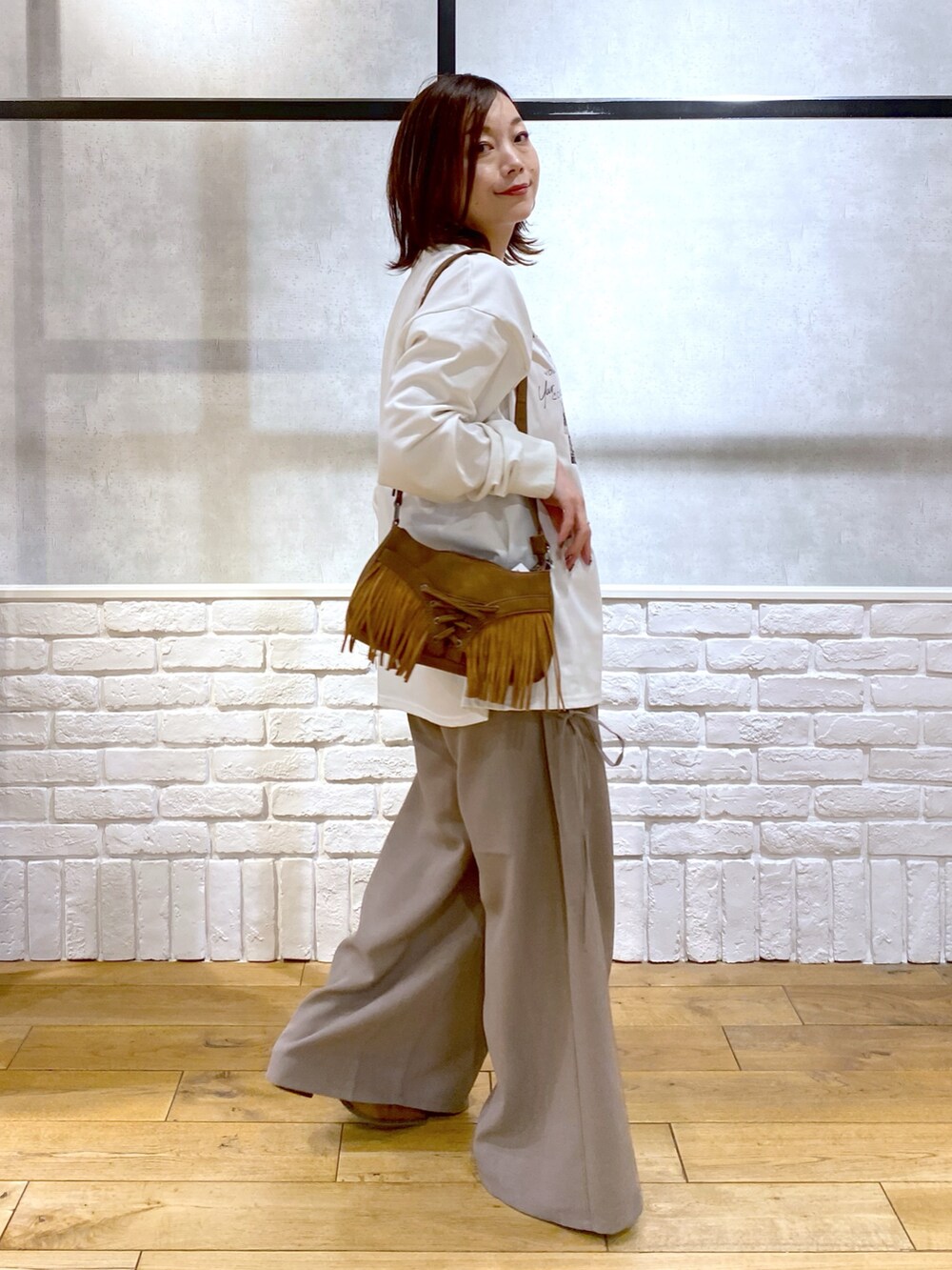 ブラウン系のスラックス、ベージュ系のショルダーバッグ、ブラウン系のパンプスを着用したレディースの春コーディネートの6枚目の写真