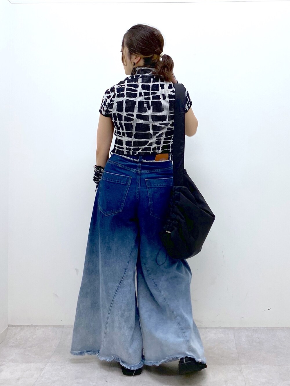 ブルー系のデニムパンツ、ブラック系のニット/セーター、ブラック系のショルダーバッグを着用したレディースの夏コーディネートの5枚目の写真