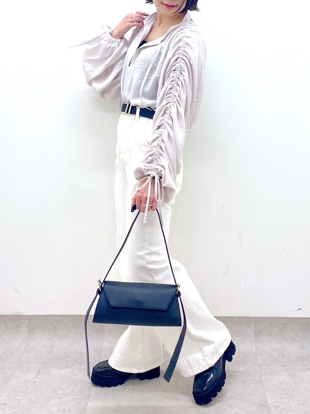 ホワイト系のパンツ、ブラック系のバッグ、ブラック系のローファーを着用したレディースの春コーディネートの4枚目の写真
