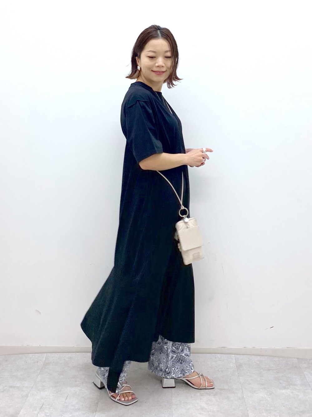 ブラック系のワンピース、ベージュ系のショルダーバッグ、シルバー系のサンダルを着用したレディースの夏コーディネートの2枚目の写真