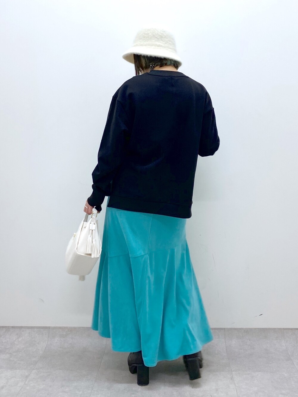 ホワイト系のショルダーバッグ、ブラック系のブーツ、ブラック系のトップスを着用したレディースの冬コーディネートの3枚目の写真