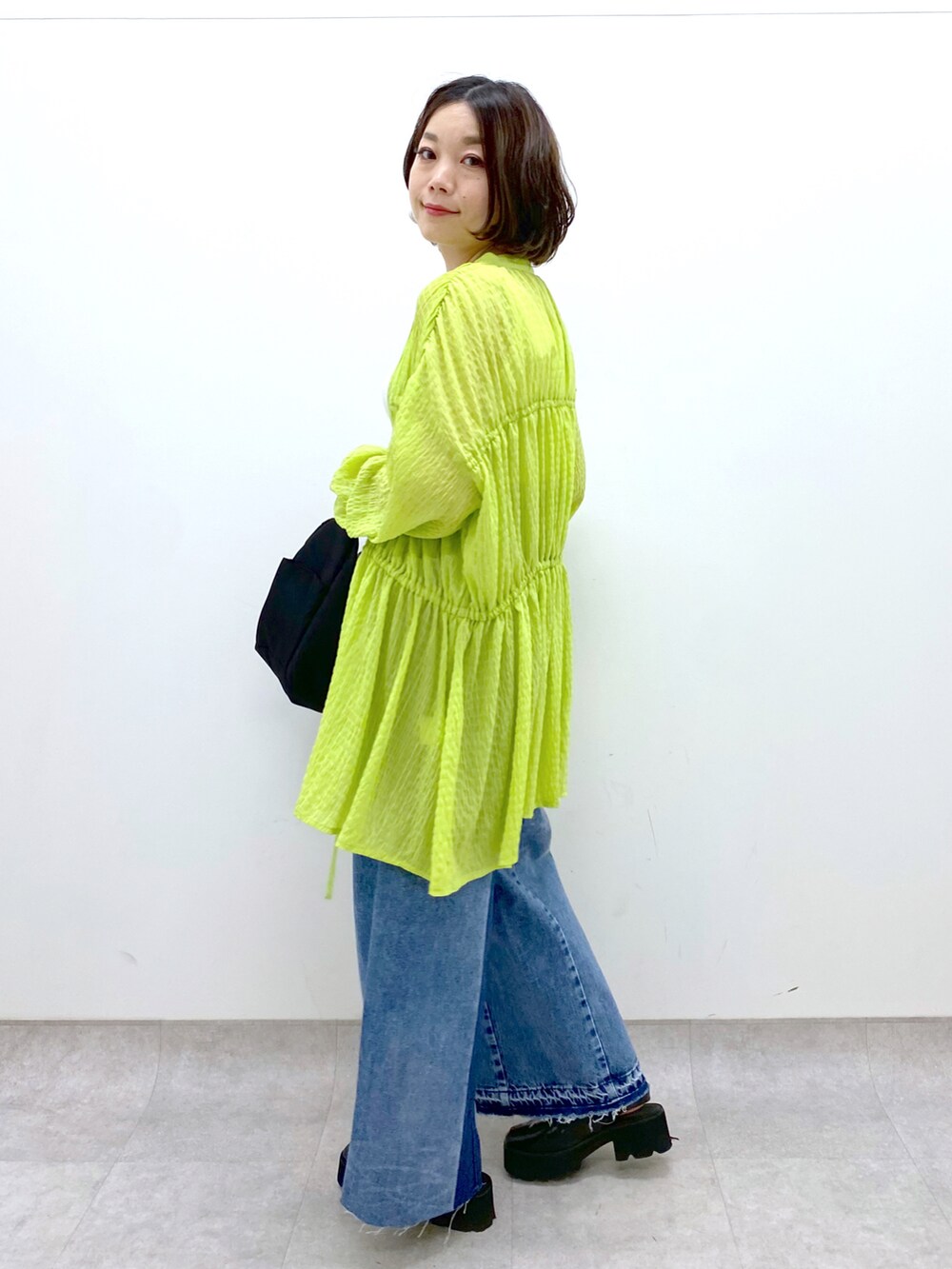 ブルー系のデニムパンツ、ホワイト系のトップス、イエロー系のトップスを着用したレディースの春コーディネートの4枚目の写真