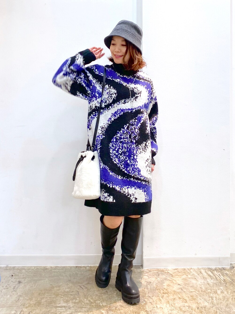 ブラック系のワンピース、ホワイト系のショルダーバッグ、ブラック系のブーツを着用したレディースの冬コーディネートの5枚目の写真