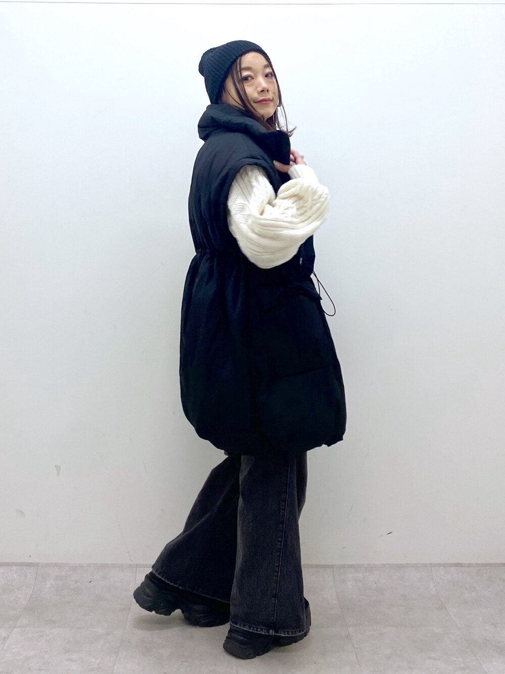 ブラック系のブルゾン、ホワイト系のニット/セーター、ブラック系のデニムパンツを着用したレディースの冬コーディネートの3枚目の写真