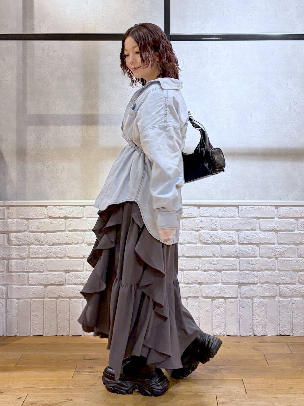 ブラック系のブーツ、ブラック系のショルダーバッグ、グレー系のスカートを着用したレディースの冬コーディネートの5枚目の写真